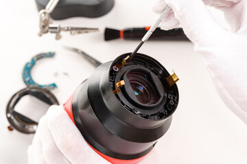 the hands of the master with gloves and a broken lens of a professional camera.