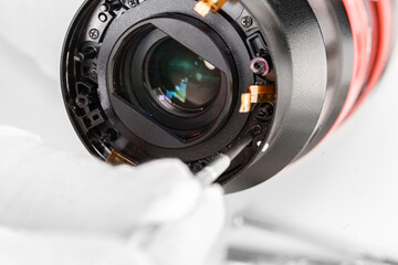 the hands of the master with gloves and a broken lens of a professional camera.
