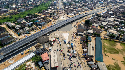 Aerial view of a bustling urban intersection with a modern overpass cutting through a dense residential area, enhancing connectivity, Asaba, Delta State, Nigeria.
