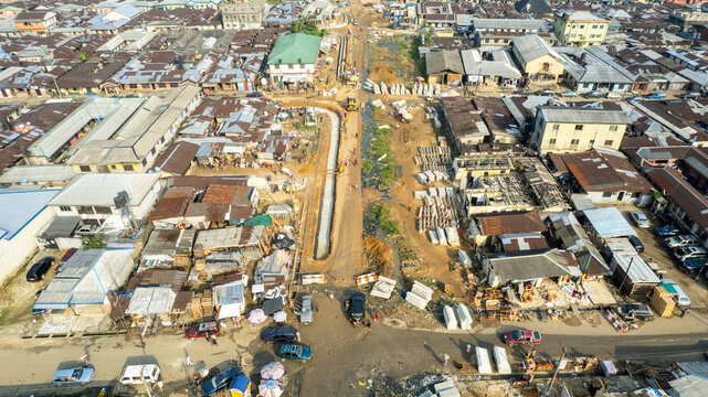 Aerial view of a construction site cutting through a densely packed urban area with buildings and vehicles, Aba, Abia, Nigeria.