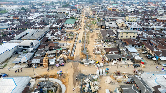Aerial view of a bustling cityscape, where a new road cuts through older buildings, creating a sharp contrast between old and new, Owerri, Nigeria.