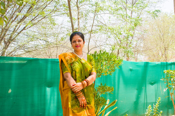 Beautiful Indian married woman in traditional green and yellow saree, bangles, bindi, sindoor,...