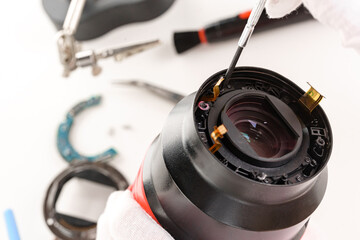 the hands of the master with gloves and a broken lens of a professional camera.