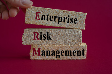 Brick blocks with words Enterprise Risk Management. Businessman hand. Beautiful red background....