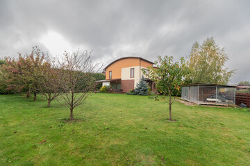 Backyard View with Green Lawn and Residential Homes Under Cloudy Sky