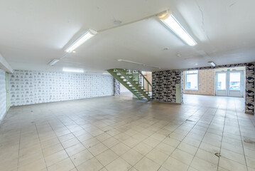 Spacious Industrial Commercial Empty Room with Tiled Floor and Green Staircase