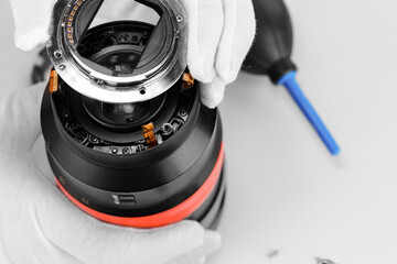 the hands of the master with gloves and a broken lens of a professional camera.