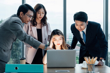 Stressed Asian businesswoman with colleagues looking at laptop in tense situation. Concept of...