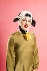 Drag Queen Showcases Crochet Cow Costume in Vibrant Studio Portrait Against Pink Backdrop