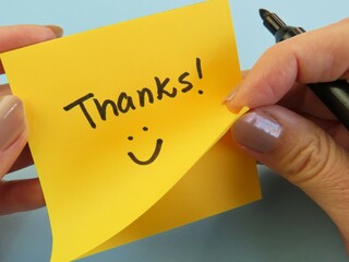 Woman hands holding a pen and a sticky note with the handwritten expression 