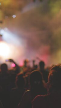 vertical shot. Passionate audience enjoying energetic rock show with raised hands, flashing lights and powerful atmosphere. feeling of live music and concert culture.