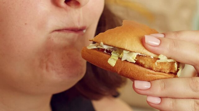 Hungry woman in a fast food cafe eating a hamburger in her hands