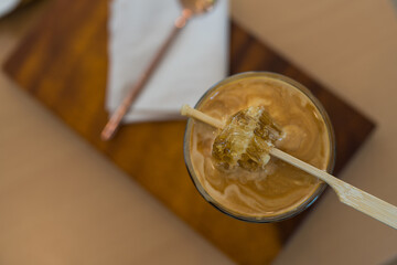 Close up photo of dirty coffee with piece honey on top. Top view
