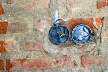 Dismantle and repair electrical outlets on brick walls.