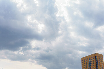 A sky with clouds and a part of a building with windows. The sky occupies most of the frame, while the building is located in the bottom right corner.
