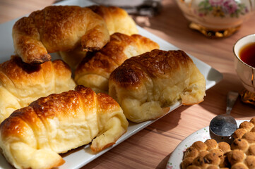 Snack or breakfast table with tea, antique crockery, croissants, cookies, camera, and map 