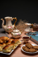 Snack or breakfast table with tea, antique crockery, croissants, cookies, camera, and map 