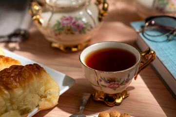 Snack or breakfast table with tea, antique crockery, croissants, cookies, camera, and map 