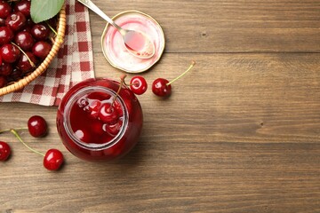 Tasty cherry jam and fresh fruits on wooden table, flat lay. Space for text