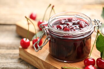 Tasty cherry jam and fresh fruits on wooden table, closeup