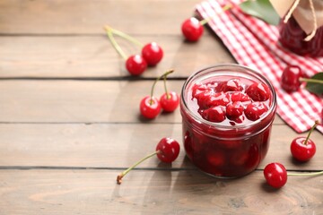 Tasty cherry jam and fresh fruits on wooden table, closeup. Space for text