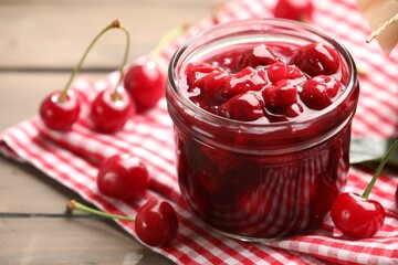 Tasty cherry jam and fresh fruits on wooden table, closeup