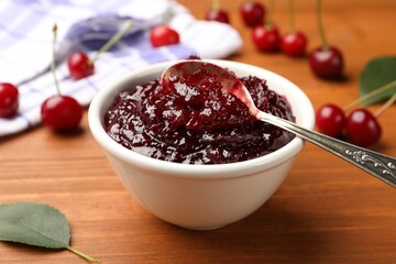 Tasty cherry jam and fresh fruits on wooden table, closeup