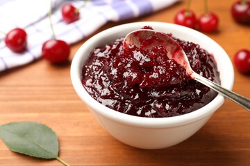 Tasty cherry jam and fresh fruits on wooden table, closeup