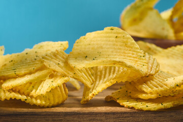Crispy flavorful chips stacked high in a bowl against a vibrant blue background