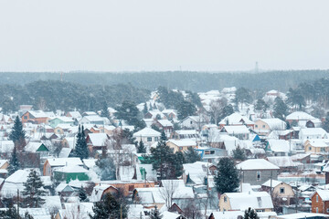 Winter wonderland envelops a quaint village in a gentle snowfall under a grey sky