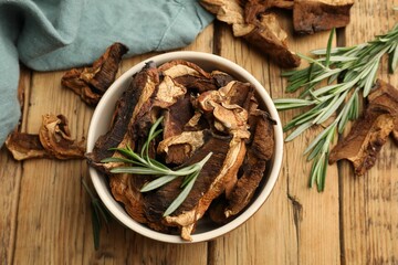 Dried chanterelle mushrooms with rosemary on wooden table, flat lay