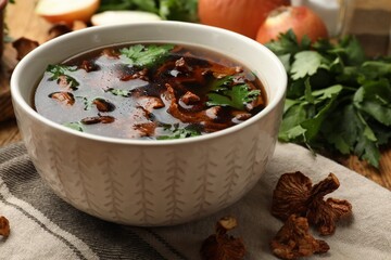 Tasty soup with mushrooms and parsley in bowl on table, closeup