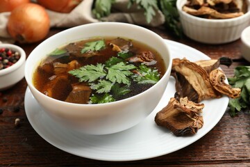 Tasty soup with mushrooms and parsley in bowl on wooden table, closeup