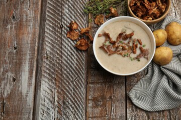 Tasty cream soup with mushrooms and thyme in bowl on color wooden table, flat lay. Space for text