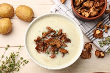Tasty cream soup with mushrooms in bowl and products on light wooden table, flat lay