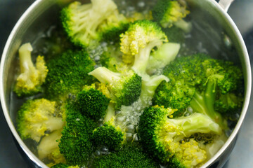 Cooking fresh broccoli in a saucepan over medium heat during a sunny afternoon