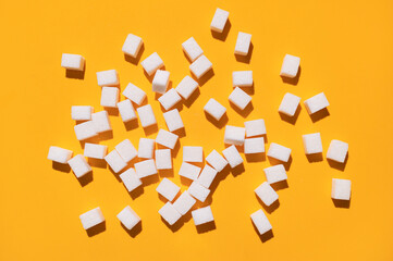 White sugar cubes on yellow background top view flat lay. Scattered sugar cubes. Abstract pattern...