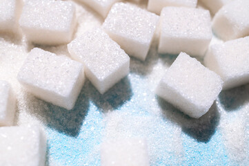 White sugar cubes on blue background top view flat lay. Scattered sugar cubes. Abstract pattern of food. Concept of sweets consumption and addiction, global issue of health 