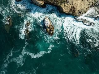 Aerial view of the rugged coastline where cliffs meet the azure ocean, with crashing waves creating a mesmerizing dance of white foam, San Diego, California, United States.