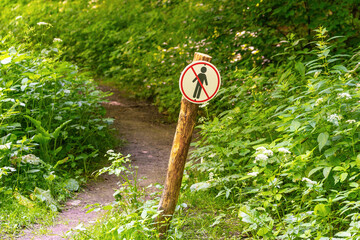 No entry sign on forest trail amidst lush greenery