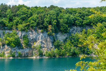 Obraz premium Scenic cliffs and lush forest reflected in tranquil lake waters. Zakrzowek lagoon. Krakow