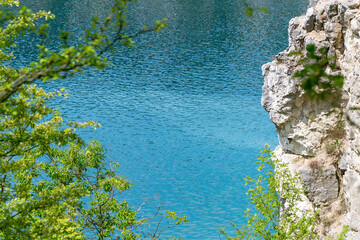 Crystal clear lake with rocky cliff and lush green foliage