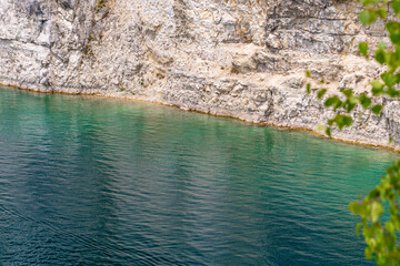 Turquoise waters against rocky cliff with green foliage in foreground