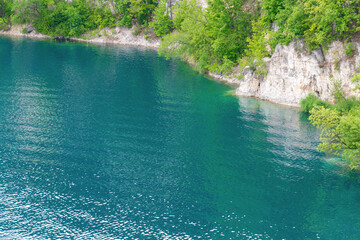 Clear blue lake surrounded by green trees and rocky cliffs