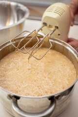 Elderly Woman Mixing Dough with a Hand Mixer