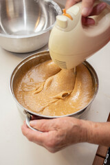 Elderly Woman Mixing Dough with a Hand Mixer