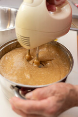 Elderly Woman Mixing Dough with a Hand Mixer