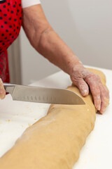 Elderly Woman Cutting Dough with a Knife