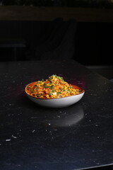 Delicious Chow mein noodles, with some chicken and veggies in it on the dark background
