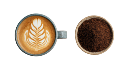 Coffee cup with latte art next to ground coffee on white background.